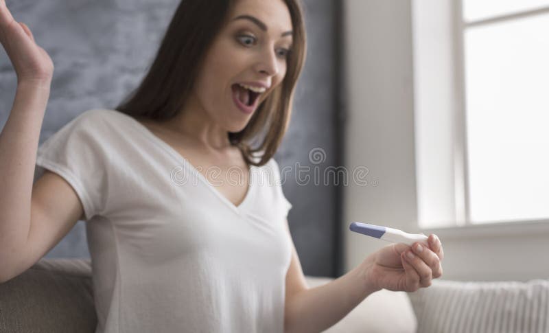 Ευτυχής νέα γυναίκα που ανακαλύπτει το θετικό αποτέλεσμα στη δοκιμή εγκυμοσύνης στοκ φωτογραφία με δικαίωμα ελεύθερης χρήσης Ευτυχής νέα γυναίκα που ανακαλύπτει το θετικό αποτέλεσμα στη δοκιμή εγκυμοσύνης στοκ φωτογραφία με δικαίωμα ελεύθερης χρήσης