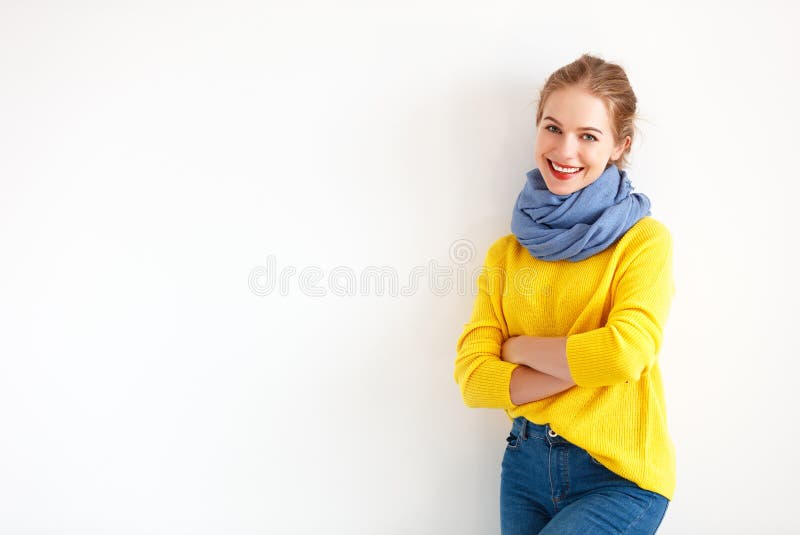 Ευτυχής νέα γυναίκα στο κίτρινο πουλόβερ στο άσπρο υπόβαθρο