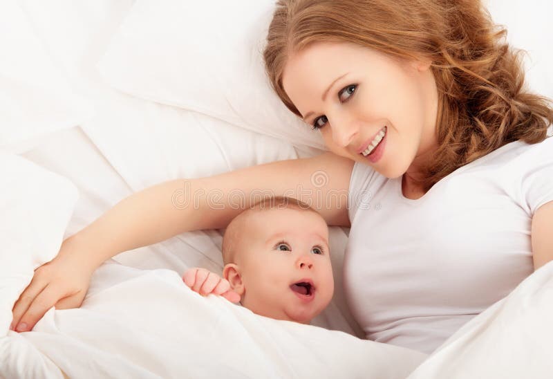 Happy family. Mother and baby lie and embrace and smiling under a blanket. Happy family. Mother and baby lie and embrace and smiling under a blanket