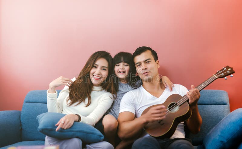 Ευτυχής οικογένεια με την κιθάρα στο σπίτι Ο γονέας βλέπει την κιθάρα παιχνιδιού κορών