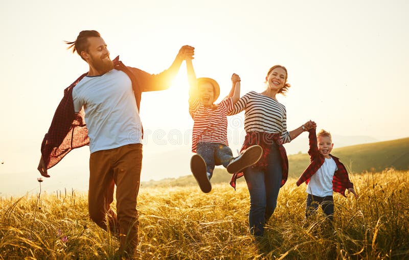 Ευτυχής οικογένεια: μητέρα, πατέρας, γιος παιδιών και κόρη στο ηλιοβασίλεμα
