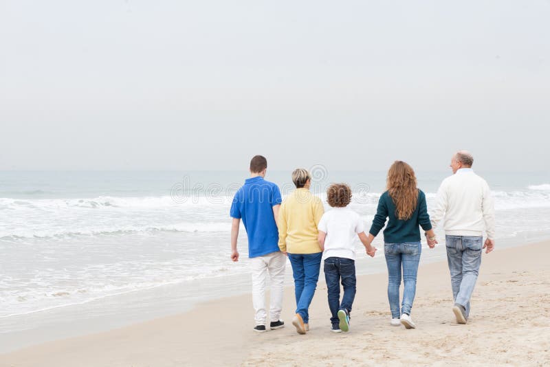 Ευτυχής οικογένεια που περπατά στην παραλία