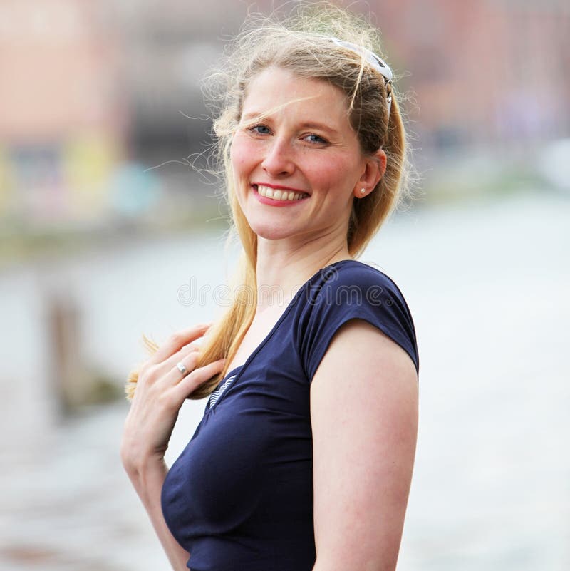 Happy joyful middle-aged woman with a lovely wide smile standing outdoors in a breeze. Happy joyful middle-aged woman with a lovely wide smile standing outdoors in a breeze