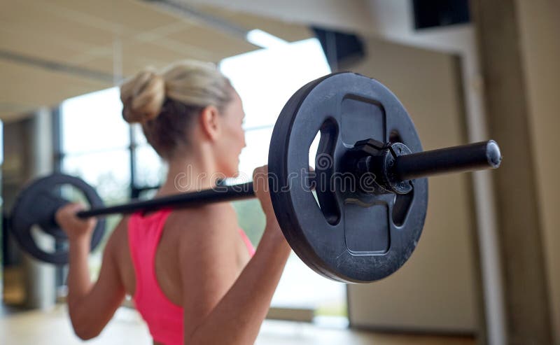 Ευτυχείς μυ'ες κάμψης γυναικών με το barbell στη γυμναστική στοκ φωτογραφία με δικαίωμα ελεύθερης χρήσης Ευτυχείς μυ'ες κάμψης γυναικών με το barbell στη γυμναστική στοκ φωτογραφία με δικαίωμα ελεύθερης χρήσης