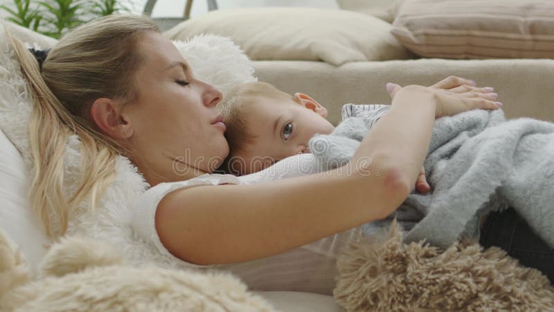 ευτυχισμένη μαμά αγκαλιάζει το παιδί της ξαπλωμένο στο σπίτι ανάμεσα σε μαξιλάρια υγιή και νοιαζόμενη για την ανάπτυξη