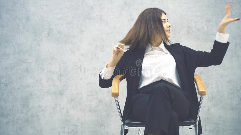 Ευτυχισμένη νεαρή επιχειρηματίας που κάθεται στην καρέκλα, και πετάει πράγματα από τον αέρα