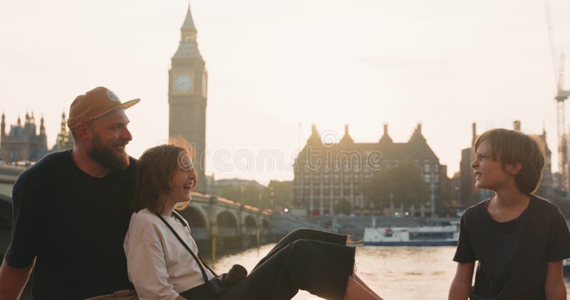 ευτυχισμένη οικογένεια πατέρα και δύο έφηβοι μιλούν και γελάνε μαζί με εκπληκτικές θέα στο λονδίνο υπό όμορφο φως του ήλιου
