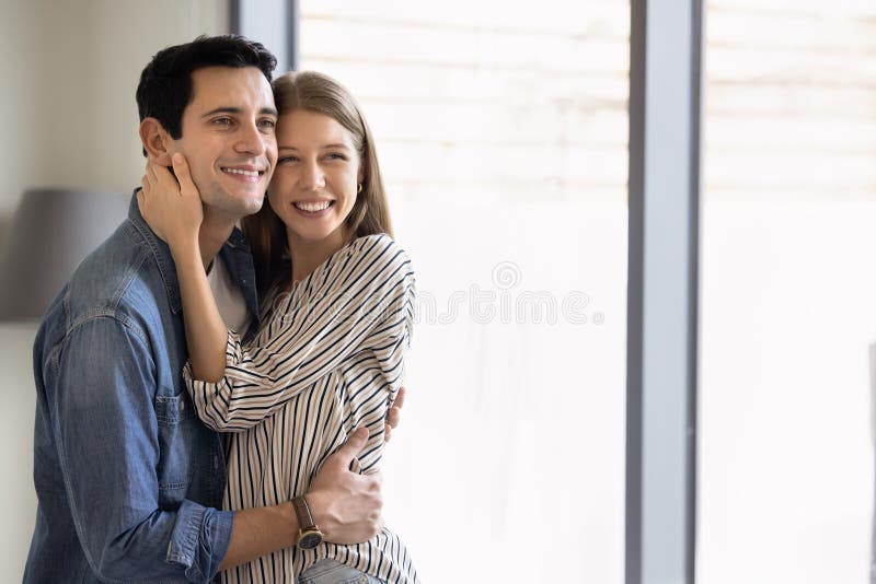 Ευτυχισμένο ελκυστικό νεαρό παντρεμένο ζευγάρι που αγκαλιάζεται στο σπίτι στοκ εικόνες με δικαίωμα ελεύθερης χρήσης
