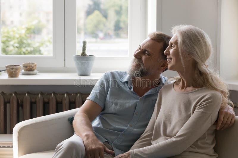 ευτυχισμένο ονειρεμένο ώριμο ζευγάρι αγκαλιασμένο στο σπίτι καναπέ με αγάπη στοκ φωτογραφία με δικαίωμα ελεύθερης χρήσης