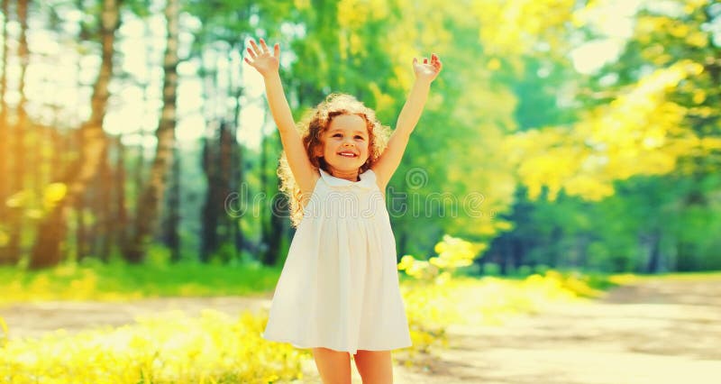 ευτυχισμένο χαρούμενο μικρό κορίτσι που διασκεδάζει σηκώνοντας τα χέρια ψηλά το ηλιόλουστο καλοκαίρι
