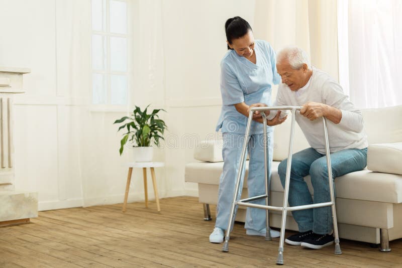 Ευχαριστημένο θετικό caregiver που βοηθά τον ασθενή της στοκ φωτογραφία με δικαίωμα ελεύθερης χρήσης Ευχαριστημένο θετικό caregiver που βοηθά τον ασθενή της στοκ φωτογραφία με δικαίωμα ελεύθερης χρήσης