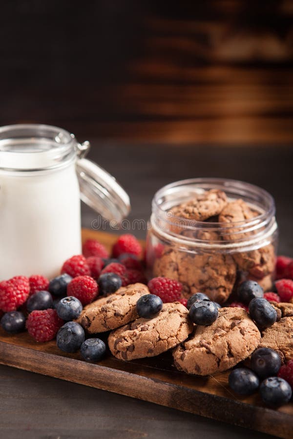 Εύγευστα oatmeal μπισκότα με τα φρέσκα σμέουρα και γάλα πέρα από τον αγροτικό ξύλινο πίνακα στοκ φωτογραφία με δικαίωμα ελεύθερης χρήσης Εύγευστα oatmeal μπισκότα με τα φρέσκα σμέουρα και γάλα πέρα από τον αγροτικό ξύλινο πίνακα στοκ φωτογραφία με δικαίωμα ελεύθερης χρήσης