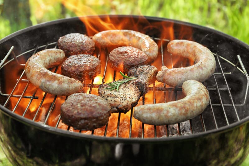 Εύγευστα μαγειρευμένα λουκάνικα με patties και μπριζόλα στη σχάρα σχαρών υπαίθρια στοκ εικόνα με δικαίωμα ελεύθερης χρήσης