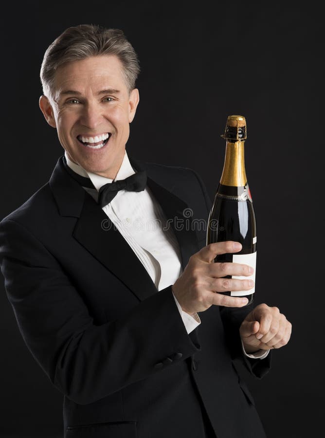 Εύθυμο άτομο στο μπουκάλι CHAMPAGNE εκμετάλλευσης σμόκιν στοκ φωτογραφία με δικαίωμα ελεύθερης χρήσης Εύθυμο άτομο στο μπουκάλι CHAMPAGNE εκμετάλλευσης σμόκιν στοκ φωτογραφία με δικαίωμα ελεύθερης χρήσης