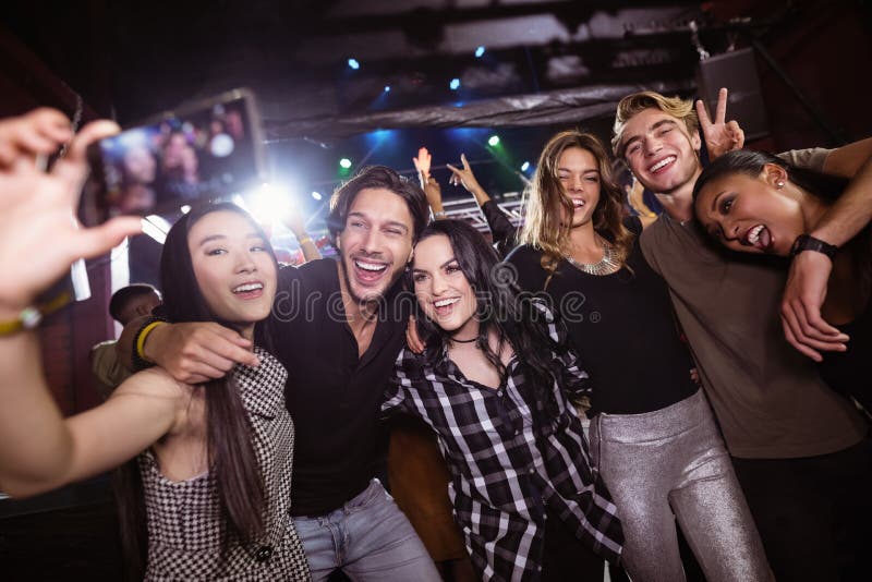 Εύθυμοι φίλοι που παίρνουν selfie απολαμβάνοντας στο νυχτερινό κέντρο διασκέδασης στοκ εικόνες