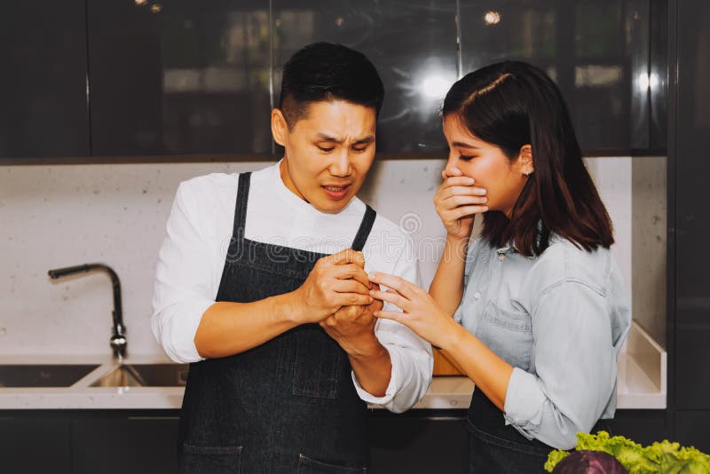 Young man suffered finger pain in an accident that was cut by a vegetable knife while cooking in the kitchen, cared for by his girlfriend with great care. Young man suffered finger pain in an accident that was cut by a vegetable knife while cooking in the kitchen, cared for by his girlfriend with great care