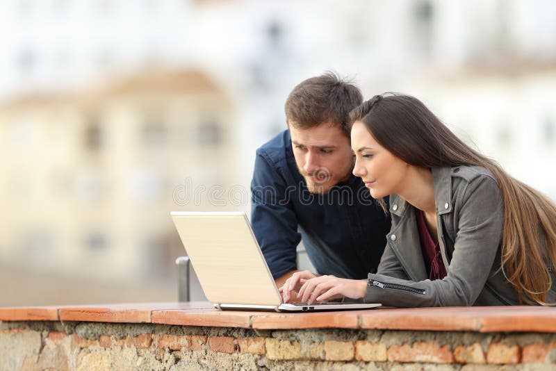 Ζεύγος που χρησιμοποιεί ένα lap-top σε ένα πεζούλι στις διακοπές στοκ εικόνα με δικαίωμα ελεύθερης χρήσης Ζεύγος που χρησιμοποιεί ένα lap-top σε ένα πεζούλι στις διακοπές στοκ εικόνα με δικαίωμα ελεύθερης χρήσης