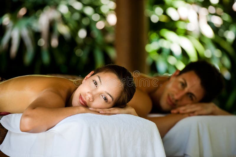 An attractive young couple lying on massage beds at a spa outdoors. An attractive young couple lying on massage beds at a spa outdoors