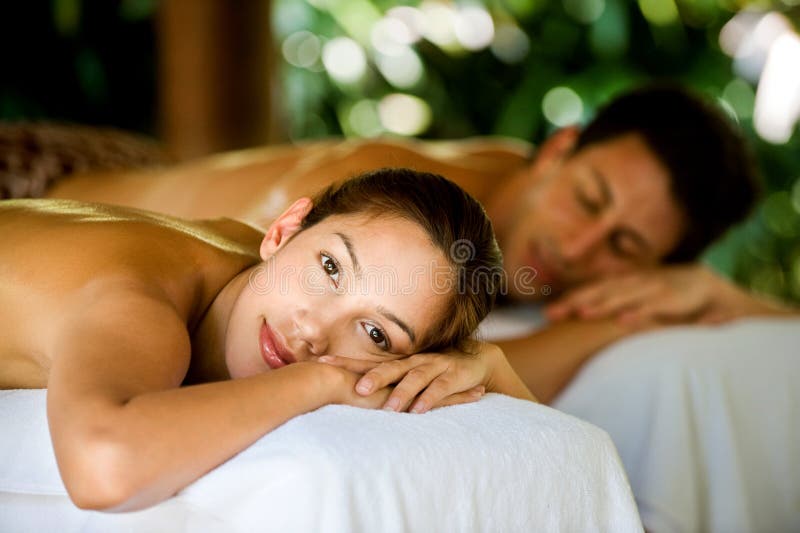 An attractive young couple lying on massage beds at a spa outdoors. An attractive young couple lying on massage beds at a spa outdoors