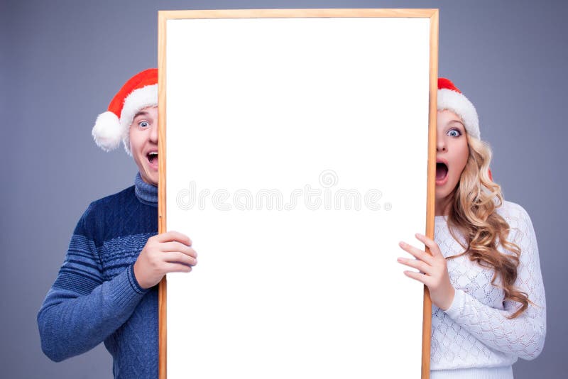 Ζεύγος Χριστουγέννων που κρατά το λευκό πίνακα με κενό
