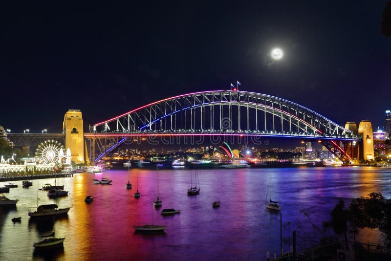 NTH SYDNEY, AUSTRALIA - JUNE 6, 2015; Scenic views across Lavender Bay, Sydney Harbour to Sydney Harbour Bridge and Sydney Opera House and city buildings during Vivid Sydney annual festival. Reflections from coloured lights illuminate the harvour in a rainbow of colour. NTH SYDNEY, AUSTRALIA - JUNE 6, 2015; Scenic views across Lavender Bay, Sydney Harbour to Sydney Harbour Bridge and Sydney Opera House and city buildings during Vivid Sydney annual festival. Reflections from coloured lights illuminate the harvour in a rainbow of colour.