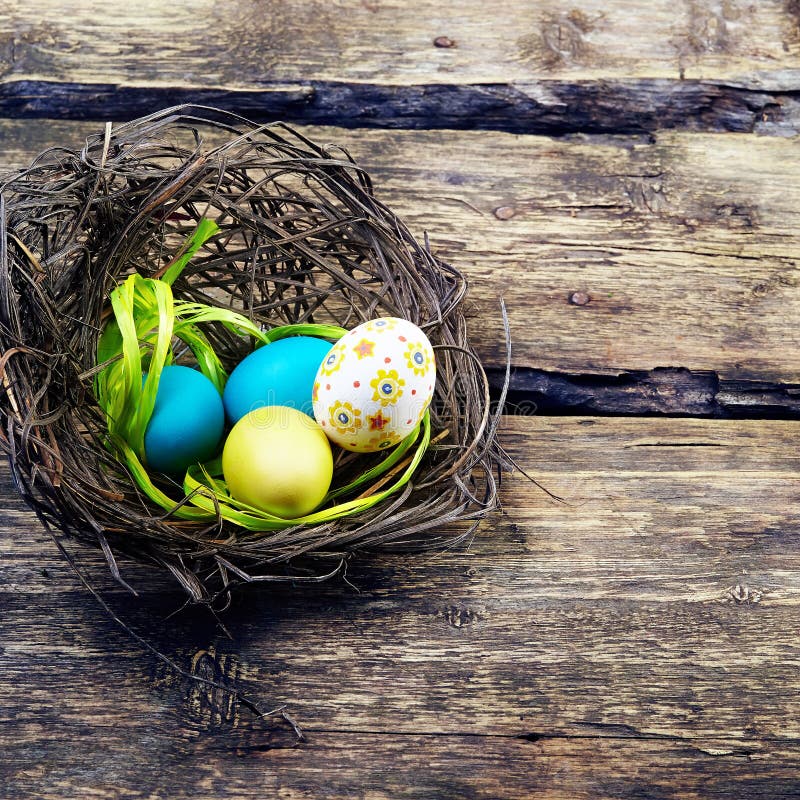 Ζωηρόχρωμα αυγά Πάσχας σε μια φωλιά στο ξύλινο υπόβαθρο