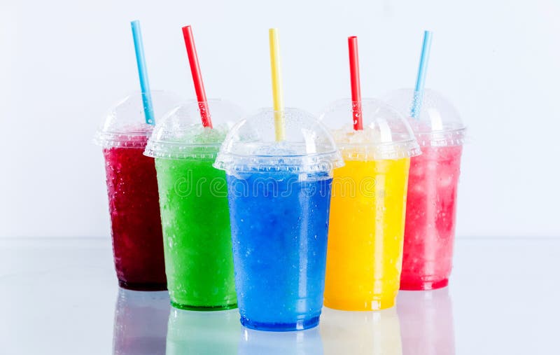 Still Life Profile of Frozen Fruit Slush Granita Drinks in Plastic Take Away Cups with Lids and Drinking Straws Arranged on Reflective Surface in front of White Background. Still Life Profile of Frozen Fruit Slush Granita Drinks in Plastic Take Away Cups with Lids and Drinking Straws Arranged on Reflective Surface in front of White Background