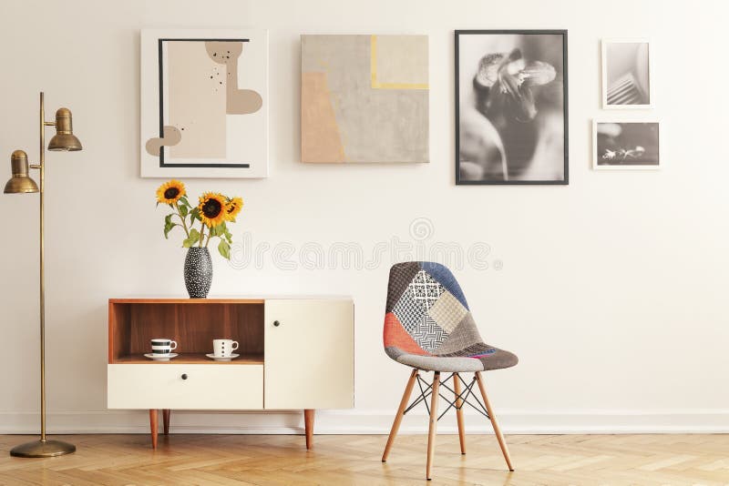 Colorful chair standing in white living room interior with gallery on wall, cupboard with flowers and tea cups in real photo. Colorful chair standing in white living room interior with gallery on wall, cupboard with flowers and tea cups in real photo