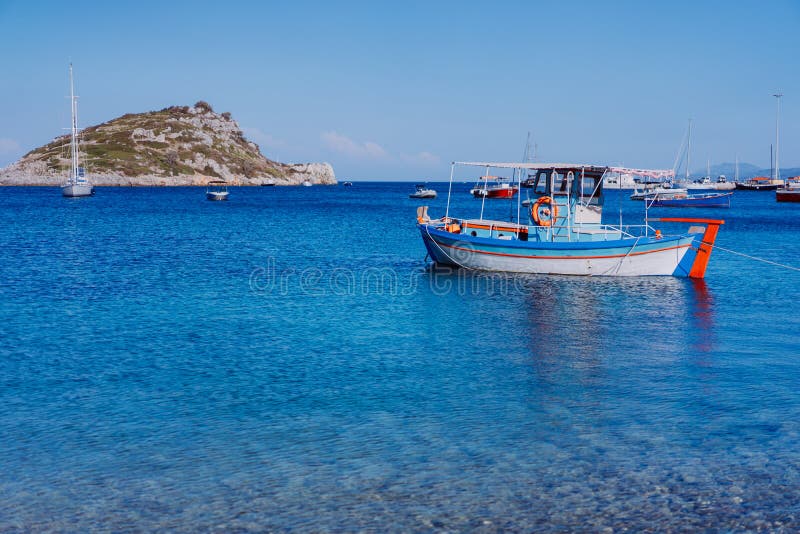 Ζωηρόχρωμο ελληνικό μεσογειακό αλιευτικό σκάφος στον ήρεμο σαφή μπλε κόλπο θαλάσσιου νερού στο πρωί αρχών του καλοκαιριού Άσπρος στοκ εικόνες με δικαίωμα ελεύθερης χρήσης