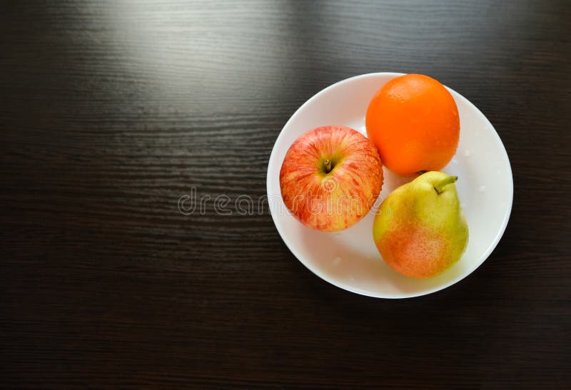 Η Apple, αχλάδι, πορτοκάλι βρίσκεται σε ένα άσπρο πιάτο στοκ εικόνες Η Apple, αχλάδι, πορτοκάλι βρίσκεται σε ένα άσπρο πιάτο στοκ εικόνες