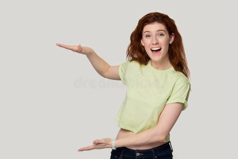 Η Redhead γυναίκα που παρουσιάζει κάτι ψηλό με τα χέρια αισθάνεται ικανοποιημένο ευτυχή στοκ εικόνες Η Redhead γυναίκα που παρουσιάζει κάτι ψηλό με τα χέρια αισθάνεται ικανοποιημένο ευτυχή στοκ εικόνες