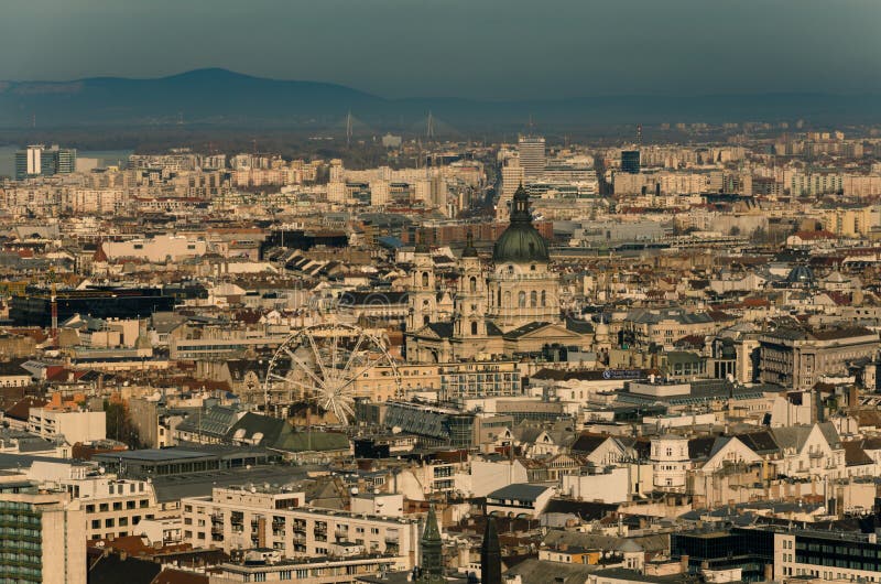 Η άποψη πέρα από τις στέγες του κέντρου της πόλης της Βουδαπέστης, η βασιλική του ST Stephen και τα ferris κυλούν στη μέση, Βουδα στοκ εικόνα Η άποψη πέρα από τις στέγες του κέντρου της πόλης της Βουδαπέστης, η βασιλική του ST Stephen και τα ferris κυλούν στη μέση, Βουδα στοκ εικόνα