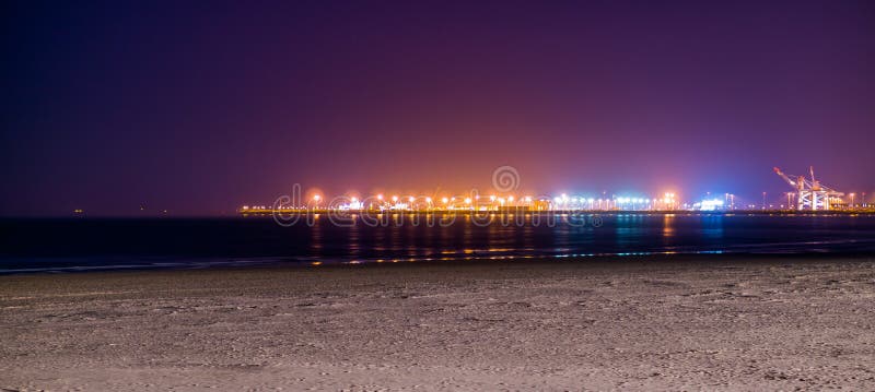 Η ακτή της παραλίας Blankenberge άναψε τή νύχτα, ζωηρόχρωμα φω'τα στην έκταση βιομηχανίας στην απόσταση στοκ φωτογραφία με δικαίωμα ελεύθερης χρήσης