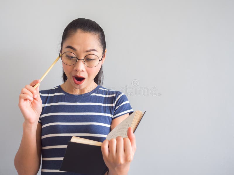 Η ασιατική γυναίκα Nerd πήρε μια έκπληκτη ιδέα από το βιβλίο στοκ εικόνα Η ασιατική γυναίκα Nerd πήρε μια έκπληκτη ιδέα από το βιβλίο στοκ εικόνα