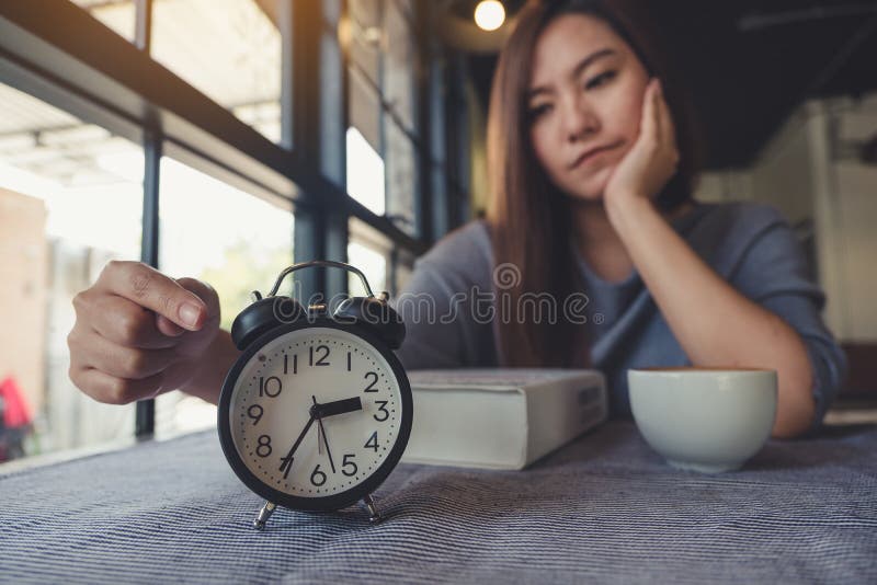 Η ασιατική υπόδειξη γυναικών σε ένα μαύρο ρολόι με το συναίσθημα τρύπησε περιμένοντας κάποιο στοκ εικόνες
