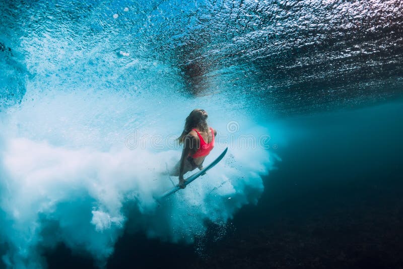 Η γυναίκα Surfer με την ιστιοσανίδα βουτά υποβρύχιος με το κατώτερο ωκεάνιο κύμα στοκ φωτογραφία με δικαίωμα ελεύθερης χρήσης Η γυναίκα Surfer με την ιστιοσανίδα βουτά υποβρύχιος με το κατώτερο ωκεάνιο κύμα στοκ φωτογραφία με δικαίωμα ελεύθερης χρήσης