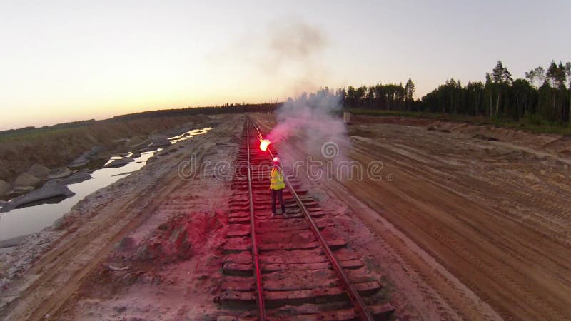 Η γυναίκα δίνει ένα σήμα ΣΤΑΣΕΩΝ για το τραίνο με την κόκκινη φλόγα