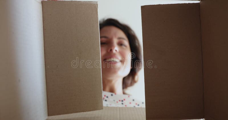 Η γυναίκα ανοίγει το δέμα κοιτώντας τα παραδοθέντα αγαθά αισθάνεται χαρούμενη