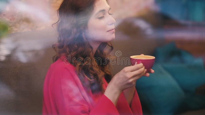 Η γυναίκα απολαμβάνει το ποτό γυαλιού καφέδων καφέ latte