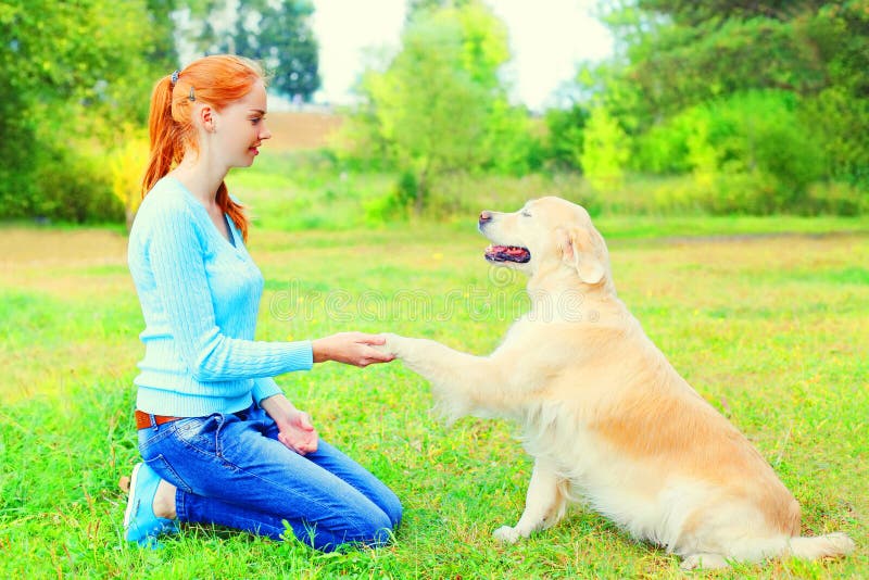 Η γυναίκα ιδιοκτητών εκπαιδεύει το χρυσό Retriever της σκυλί στη χλόη στοκ φωτογραφία Η γυναίκα ιδιοκτητών εκπαιδεύει το χρυσό Retriever της σκυλί στη χλόη στοκ φωτογραφία