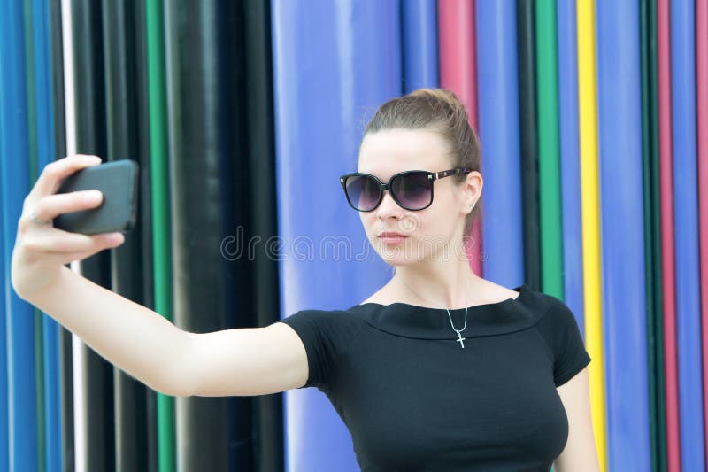 Η γυναίκα κάνει selfie με το smartphone στο Παρίσι, Γαλλία Γυναίκα με το κινητό τηλέφωνο στο ζωηρόχρωμο υπόβαθρο Κορίτσι στα γυαλ στοκ εικόνα