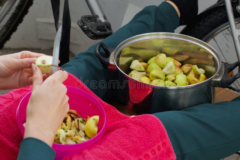 Η γυναίκα ξεφλουδίζει τα μήλα και βάζει τα φέτες σε ένα λουκάνικο στοκ εικόνες