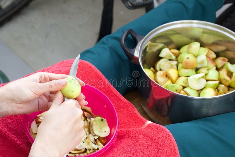 Η γυναίκα ξεφλουδίζει τα μήλα και βάζει τα φέτες σε ένα λουκάνικο στοκ εικόνες
