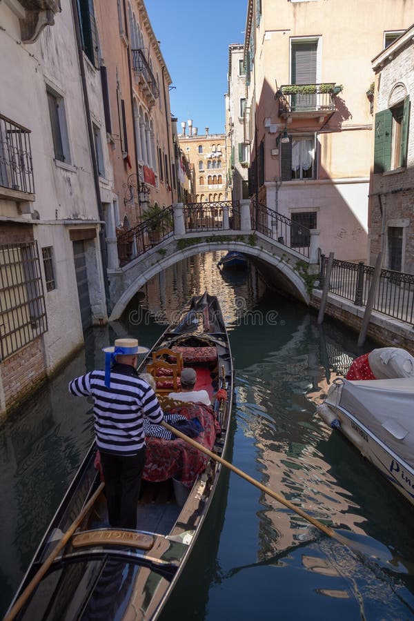 Η γόνδολα με gondolier έντυσε στο κλασικό κοστούμι σε ένα στενό κανάλι στη Βενετία στοκ φωτογραφίες με δικαίωμα ελεύθερης χρήσης Η γόνδολα με gondolier έντυσε στο κλασικό κοστούμι σε ένα στενό κανάλι στη Βενετία στοκ φωτογραφίες με δικαίωμα ελεύθερης χρήσης