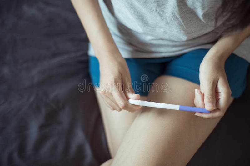 Η δοκιμή εγκυμοσύνης εκμετάλλευσης χεριών γυναικών μετά από να εξετάσει στην κρεβατοκάμαρά της, κλείνει επάνω στοκ εικόνα