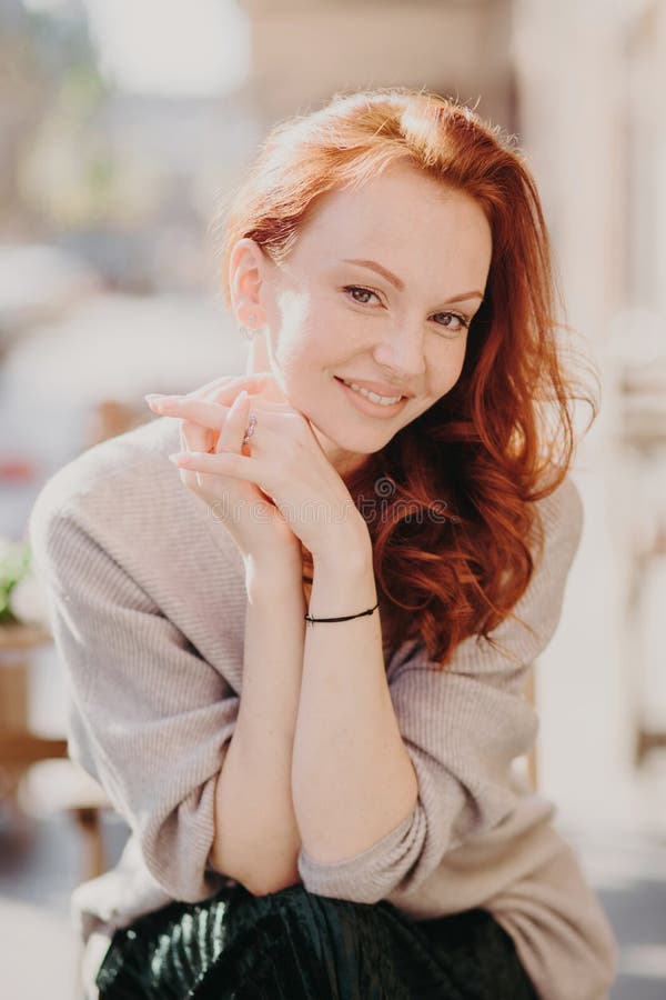 Η εικόνα του καλού redhead θηλυκού προτύπου χαμογελά ευτυχώς, έχει το υγιές δέρμα, αποτελεί, κρατά τα χέρια μαζί, που ντύνονται σ στοκ φωτογραφίες με δικαίωμα ελεύθερης χρήσης Η εικόνα του καλού redhead θηλυκού προτύπου χαμογελά ευτυχώς, έχει το υγιές δέρμα, αποτελεί, κρατά τα χέρια μαζί, που ντύνονται σ στοκ φωτογραφίες με δικαίωμα ελεύθερης χρήσης