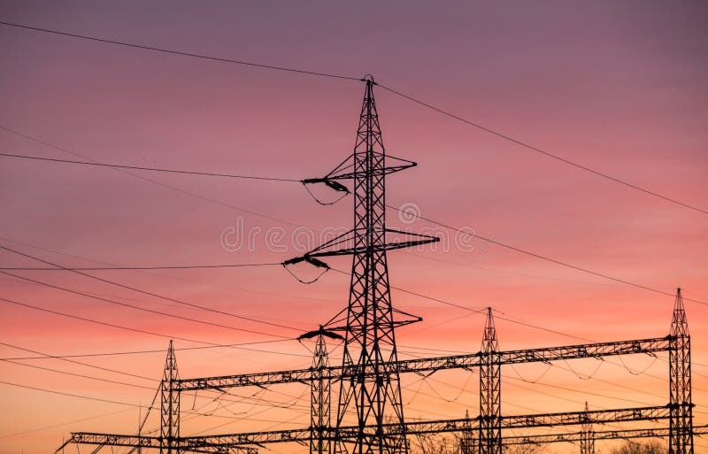 High voltage electric poles conducting electrical power during sunset. High voltage electric poles conducting electrical power during sunset