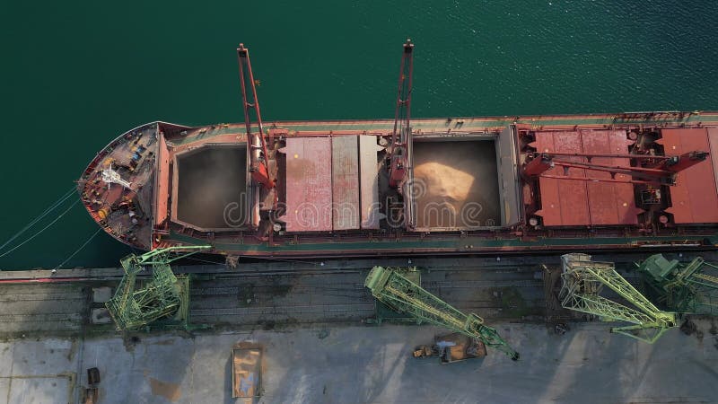 η εναέρια άποψη του μεγάλου πλοίου μεταφοράς χύδην φορτίου φορτώνεται με σιτάρι στο λιμάνι κατά το ηλιοβασίλεμα