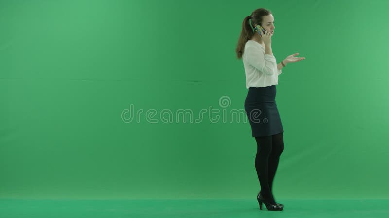 Η επιχειρησιακή γυναίκα μιλά στο κινητά τηλέφωνο και το περπάτημα κυττάρων της Φορά το επίσημο φόρεμα: άσπρες πουκάμισο και blak