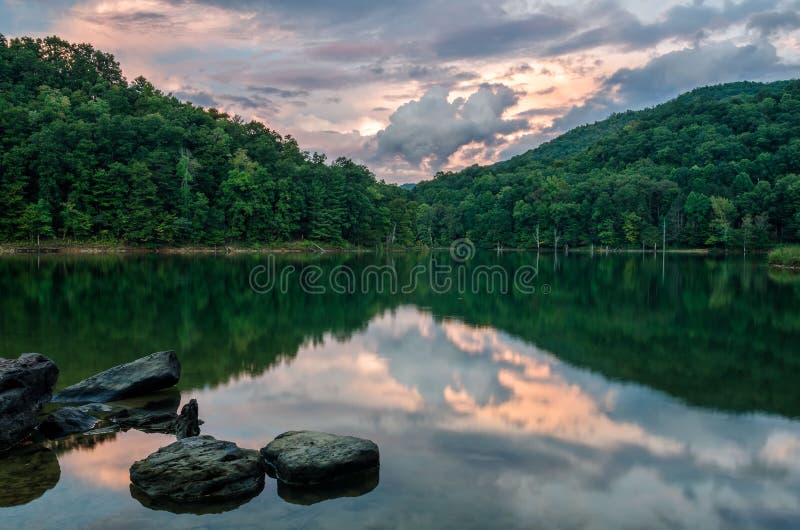 A beautiful pastel sunset reflects in the still waters of Martins Fork lake in the Appalachian Mountains of Kentucky. A beautiful pastel sunset reflects in the still waters of Martins Fork lake in the Appalachian Mountains of Kentucky.